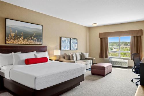 a hotel room with a large bed and a couch at Ramada by Wyndham Drumheller Hotel & Suites in Drumheller