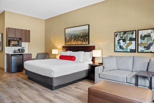 a hotel room with a bed and a couch at Ramada by Wyndham Drumheller Hotel & Suites in Drumheller