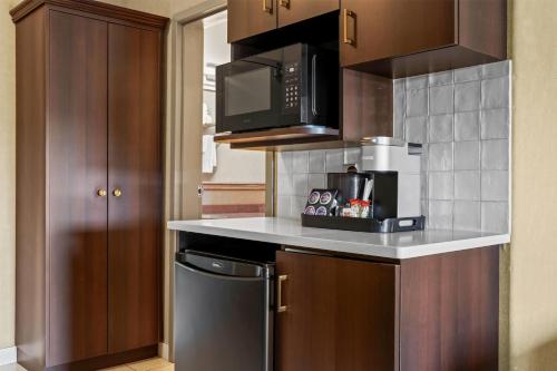 a small kitchen with a microwave and a stove at Ramada by Wyndham Drumheller Hotel & Suites in Drumheller