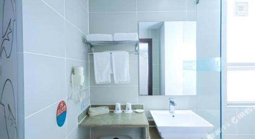 a white bathroom with a sink and a mirror at GreenTree Inn Nanning Langdong Hotel in Nanning