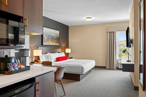 a hotel room with a bed and a kitchen at Ramada by Wyndham Drumheller Hotel & Suites in Drumheller