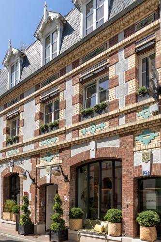 a brick building with windows and potted plants at Les 2 Villas in Trouville-sur-Mer