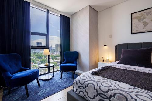 a bedroom with a bed and two chairs and a window at Premier Suites- Panoramic View in Cebu City