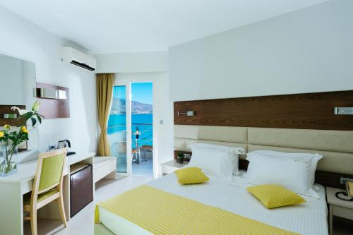 a bedroom with a bed with yellow pillows and a kitchen at Elounda Akti Olous (Adults Only) in Elounda