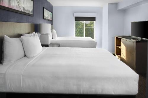 a hotel room with a large white bed and a window at Hyatt House Morristown in Morristown
