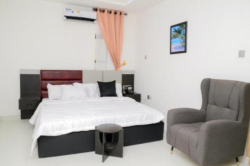 a bedroom with a bed and a chair at Exodus Resort& Suites in Ilorin