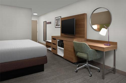 a hotel room with a desk with a bed and a mirror at Hampton Inn Butte in Butte