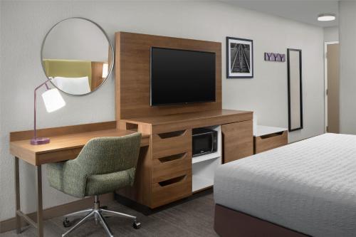 a room with a desk with a television and a mirror at Hampton Inn Butte in Butte