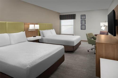 a hotel room with two beds and a desk at Hampton Inn Butte in Butte