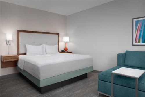 a bedroom with a bed and a blue chair at Hampton Inn and Suites by Hilton Vero Beach-Downtown in Vero Beach