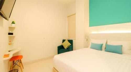 a white bedroom with a bed and a chair at Makassar Beach Inn in Makassar