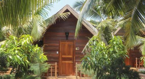 a wooden cabin with a wooden door and some trees at HON BA LAGI BEACH RESORT in La Gi