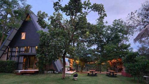 a black house with picnic tables in front of it at Kaitoon's River House in Ratchaburi