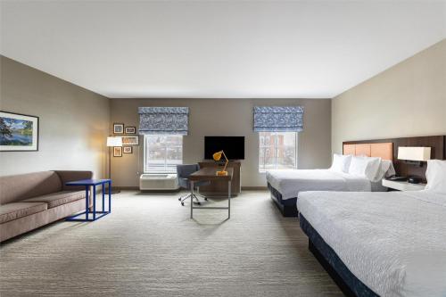 洛根Hampton Inn And Suites Logan, Ut的有两张床和一张沙发的酒店房间