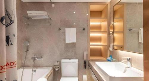 a bathroom with a toilet and a sink and a tub at Dalian Bohai Pearl Hotel in Dalian
