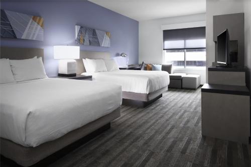 a hotel room with two beds and a flat screen tv at Hyatt House The Woodlands-Shenandoah in Shenandoah