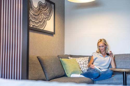 a woman sitting on a couch reading a book at Hyatt House The Woodlands-Shenandoah in Shenandoah