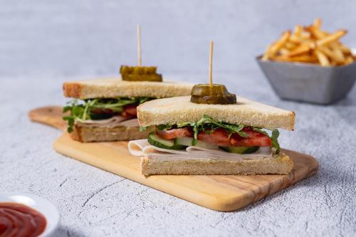 two sandwiches on a cutting board with a bowl of fries at Hyatt House The Woodlands-Shenandoah in Shenandoah