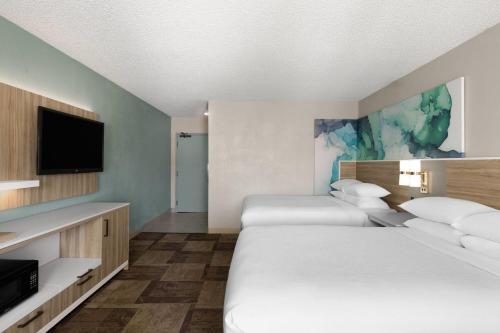 a hotel room with two beds and a flat screen tv at Wyndham Garden Newark Fremont Silicon Valley in Newark