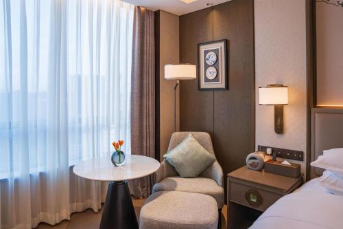 a hotel room with a table and a chair and a window at Yuexiu Hotel Guangzhou,Curio Collection by Hilton-Free shuttle between hotel and Exhibition Center during Canton Fair & Exhibitor Registration Counter in Guangzhou