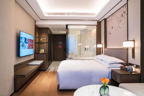 a hotel room with a bed and a tv at Yuexiu Hotel Guangzhou,Curio Collection by Hilton-Free shuttle between hotel and Exhibition Center during Canton Fair & Exhibitor Registration Counter in Guangzhou