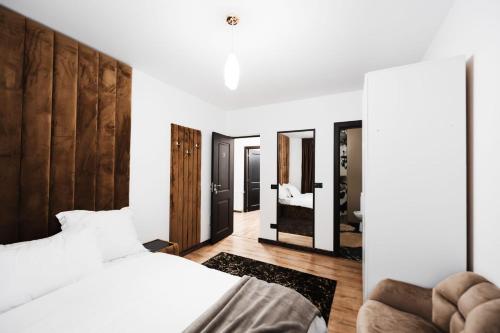a bedroom with a white bed and a mirror at Cabana La Conac in Borşa