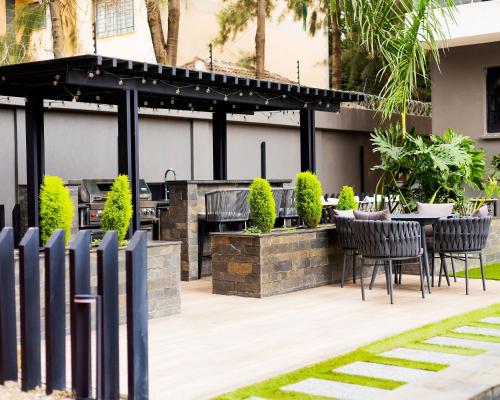 a patio with a grill and tables and chairs at Pretty haven-studio apartment -Kilimani in Nairobi