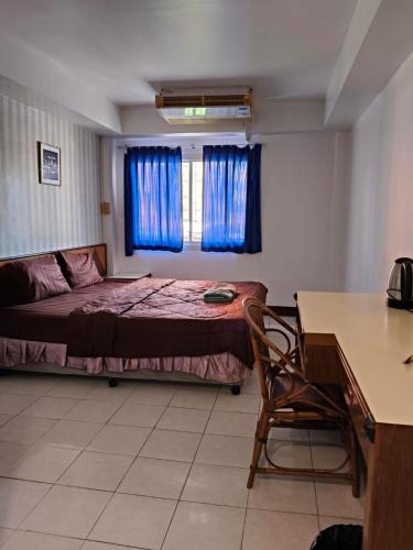 a bedroom with a bed and a table and a desk at Naza Orchid Pattaya in Pattaya South