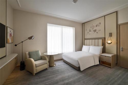 a bedroom with a bed and a chair and a window at Signia by Hilton in Amman