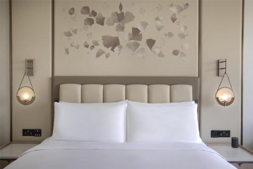 a bedroom with a white bed with two lights above it at Signia by Hilton in Amman