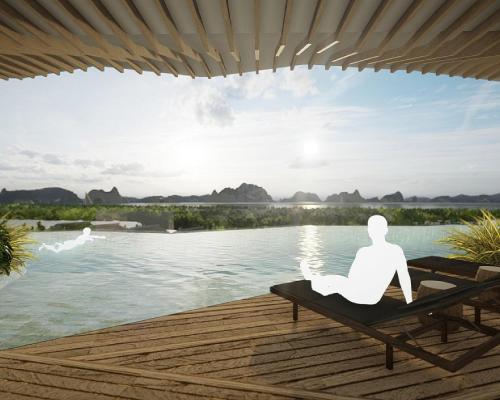 a man sitting on a chair next to a body of water at Hyatt Place Ha Long Bay, Bai Chay in Ha Long