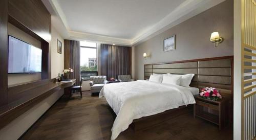 a bedroom with a large bed and a television at Hanyong Hotel Shenzhen International Exhibition Center in Shenzhen