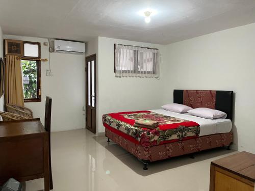 a bedroom with a bed with a red blanket at Hotel Pison in Rantepao