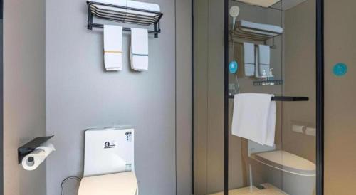 a bathroom with a toilet and a toilet paper dispenser at City Comfort Inn Wuhan Hankou Railway Station West Square in Wuhan