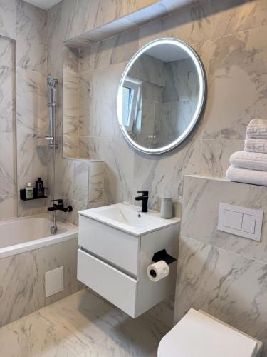 a white bathroom with a sink and a mirror at Modern Spacious Mountain View Apt in Braşov