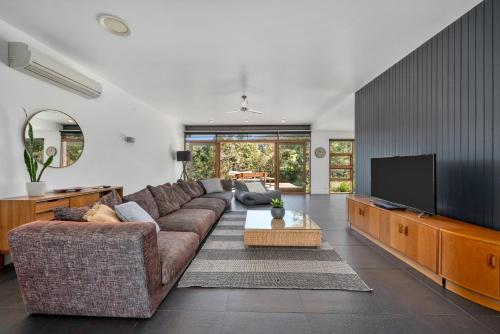a living room with a couch and a flat screen tv at Huon Valley House in Ranelagh