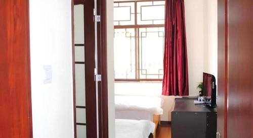 a bedroom with a bed and a window with red curtains at Lijiang Peach Hostel in Lijiang
