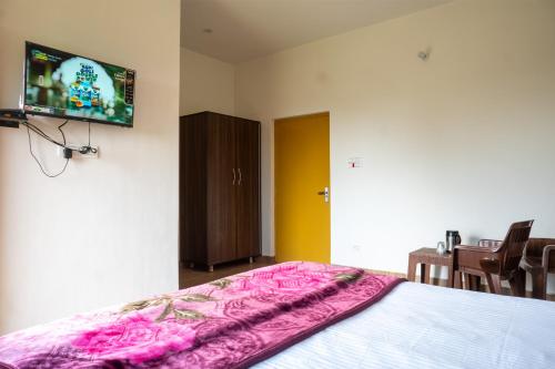 een slaapkamer met een bed en een flatscreen-tv bij Nature's View Kandwari in Pālampur