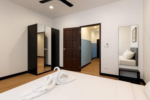 a bedroom with a bed with white sheets and mirrors at Payton House Patong - Newly Renovated in Patong Beach