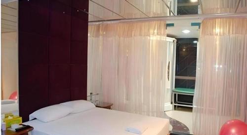 a bedroom with a bed and a window with curtains at Out Sky Hotel in Huizhou