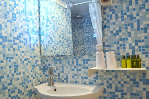 a blue tiled bathroom with a sink and a mirror at Apsenti couples only in Agios Ioannis Mykonos