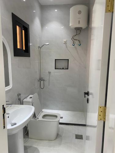 a white bathroom with a toilet and a sink at شقق الضباب 2 in Al Baha