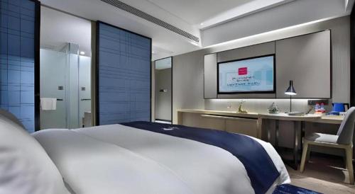 a bedroom with a bed and a desk and a television at Echarm Hotel Guilin North High Speed Railway Station in Guilin