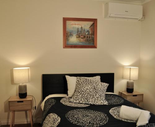 a bedroom with a bed with two lamps and a painting at Long Island Beach House gateway to Mornington Peninsula#Free parking in Frankston