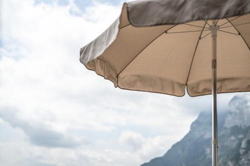 a tan umbrella in front of a mountain at Hotel Arcobaleno in Fai della Paganella