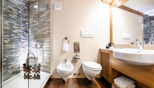 a bathroom with a sink and a toilet and a shower at Hotel Arcobaleno in Fai della Paganella