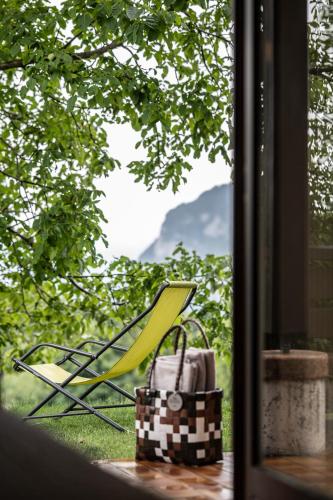 a yellow chair and a purse sitting next to a window at Hotel Arcobaleno in Fai della Paganella
