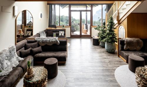 a living room with couches and tables and windows at Hotel Arcobaleno in Fai della Paganella