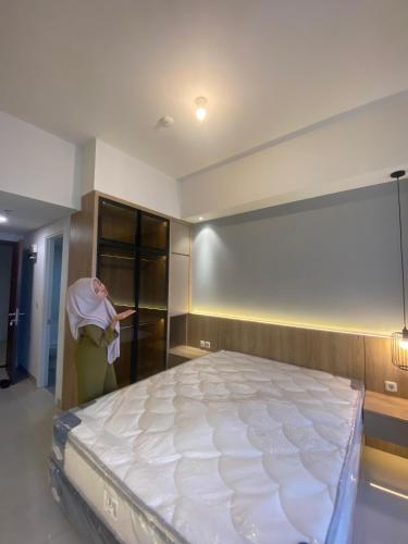 a woman standing in a room with a large bed at Room house avenue BSD in Curug 3