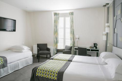 a hotel room with two beds and a desk at Hôtel A La Villa des Artistes in Paris